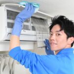 エアコンに付いたほこりを掃除する男性